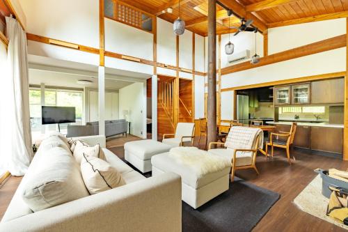a living room with a couch and a dining room at 那須プレミアムハウス 高級感あふれる内装 カラオケ 卓球 薪ストーブ in Nasu