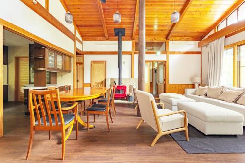 a living room with a table and chairs and a couch at 那須プレミアムハウス 高級感あふれる内装 カラオケ 卓球 薪ストーブ in Nasu