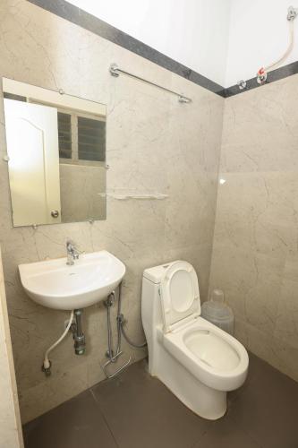 a bathroom with a white toilet and a sink at Nilan Zingle Resort in Puducherry