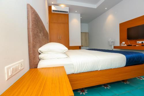 a bedroom with a large bed and a television at Nilan Zingle Resort in Puducherry