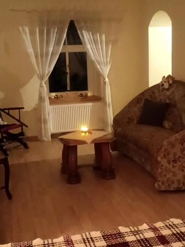 a living room with a table and a couch and a window at STĀRĶA APARTAMENTI in Kuldīga