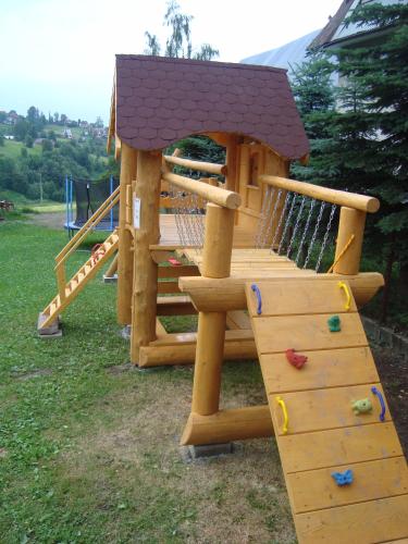 a wooden playground with a slide and a play structure at Apartamenty i pokoje Pod Limbami - sauna, tężnia in Bukowina Tatrzańska