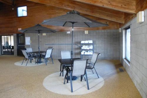 a dining room with tables and chairs and umbrellas at AmericInn by Wyndham Mitchell in Mitchell