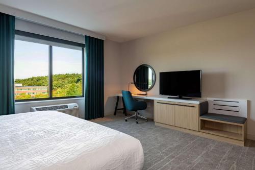 a hotel room with a bed and a desk with a television at Hilton Garden Inn Boston Canton, Ma in Canton