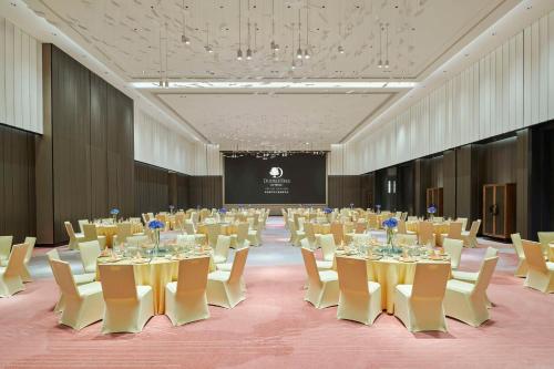 a conference room with tables and chairs and a screen at DoubleTree by Hilton Zhuhai Hengqin in Zhuhai