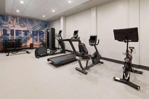 a gym with several exercise bikes and a flat screen tv at Riverbend Hotel and Suites, Trademark Collection by Wyndham in Ashtabula