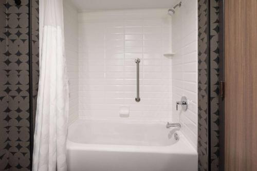 a white bath tub in a bathroom with a shower at Riverbend Hotel and Suites, Trademark Collection by Wyndham in Ashtabula