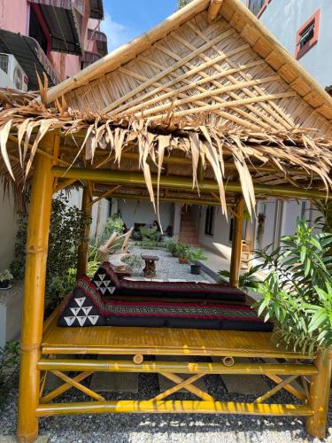 a wooden gazebo with a bench in a yard at Flora Hostel KhaoSok in Khao Sok