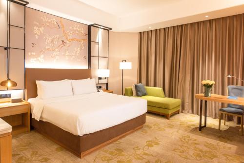 a hotel room with a bed and a chair at Rising Dragon International Hotel in Dongguan