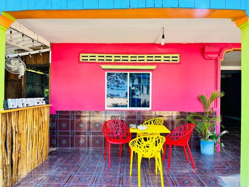 a table and chairs in front of a red wall at Happiness Guesthouse in Koh Rong Sanloem