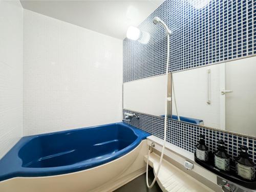 a bathroom with a blue tub and a mirror at Hotel Amethyst in Tokyo