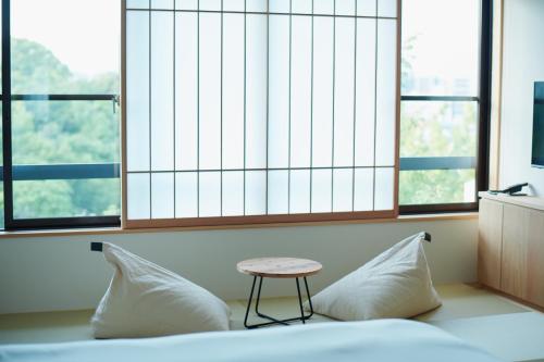 a bed with two pillows and a stool in a room with windows at くろしお想 in Shirahama