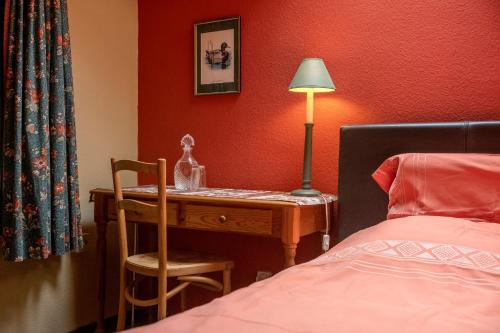 a bedroom with a desk with a lamp and a bed at B&B Het Loonderhof in Borgloon