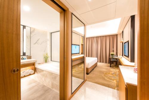 a bathroom with a bath tub and a bedroom at Rising Dragon International Hotel in Dongguan