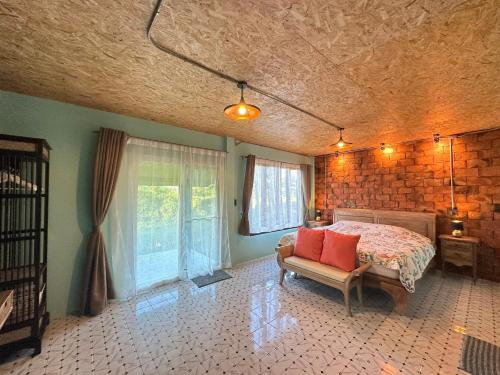 a bedroom with a bed and a chair and windows at SukhothaiNeeDee FarmCafe in Sukhothai