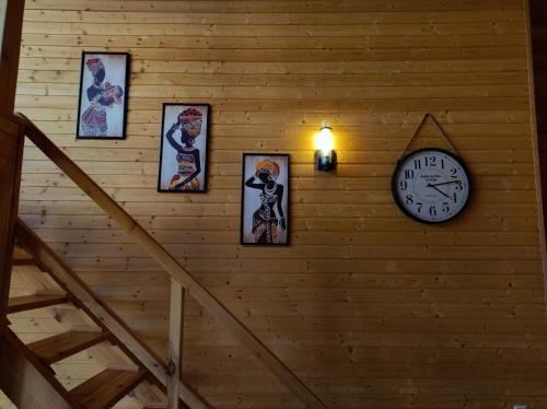 a wall with a clock and pictures on it at Wooden Villa Sormoni in Tskaltubo