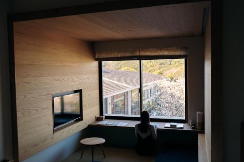 a woman sitting at a desk in a room with a window at くろしお想 in Shirahama