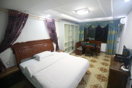 a bedroom with a bed and a table and a chair at LQJ Riverside Guest House in Fenghuang