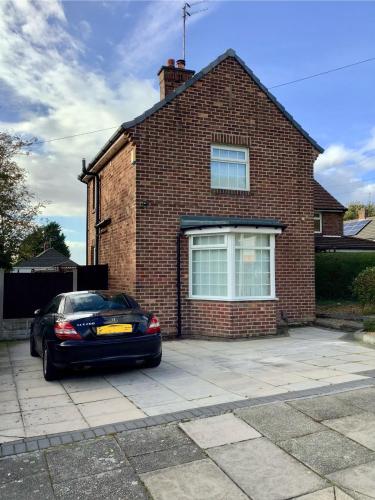 a car parked in front of a brick house at Lorton Villa with a Log Burner in Saint Helens