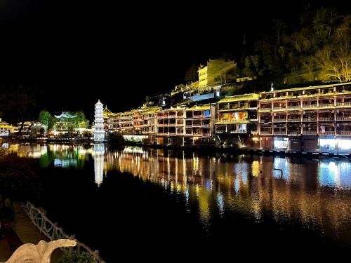 a city lit up at night next to a body of water at LQJ Riverside Guest House in Fenghuang