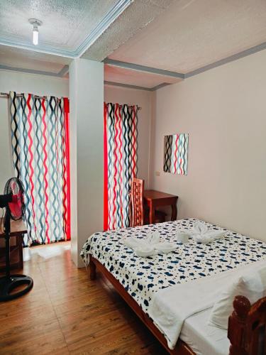 a bedroom with a bed and two large windows at Bogah Lodge in Banaue