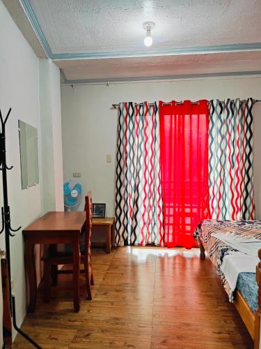a room with a bed and a table and a red curtain at Bogah Lodge in Banaue