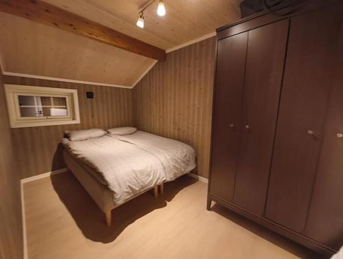 a small bedroom with a bed and a cabinet at Hytte-23 Cozy cabin close to Kvitfjell in Fåvang