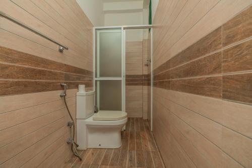a bathroom with a toilet and wooden walls at The Calm Of8 in Unawatuna