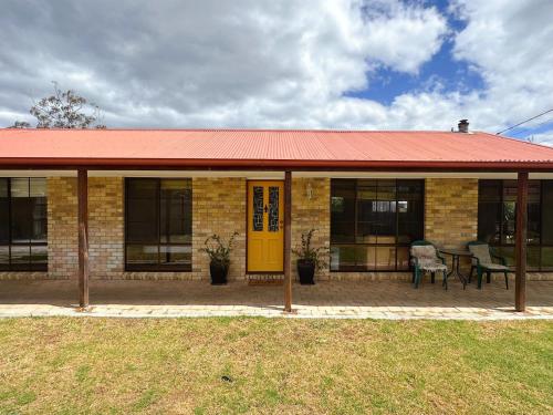 a brick building with a red roof and a yellow door at Seven Mile Beach House - 5 minutes to the Airport in Seven Mile Beach