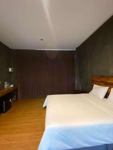 ein Schlafzimmer mit einem großen weißen Bett und einem Holzboden in der Unterkunft boomresort in Ron Phibun