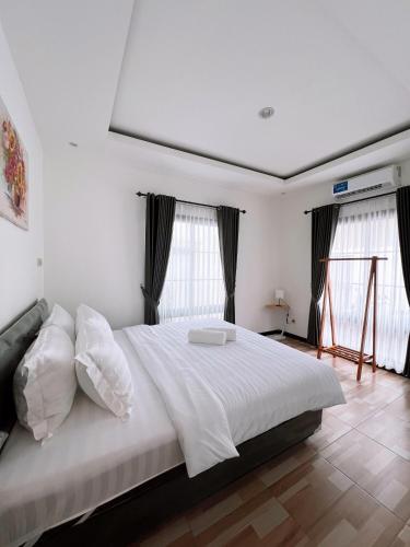 a bedroom with a large bed with white sheets and pillows at Casa de Gaudete 3 Bedroom King Size Villa Lembang in Genteng