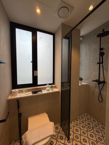 a bathroom with a shower and a sink and a window at ISA Hotel Amber Road in Singapore