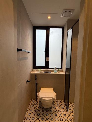 a bathroom with a toilet and a window at ISA Hotel Amber Road in Singapore
