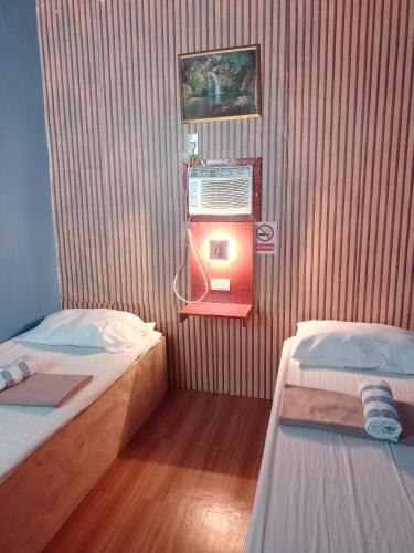 a small room with two beds and a fan at Angler's Hub & Resort Oslob in Oslob