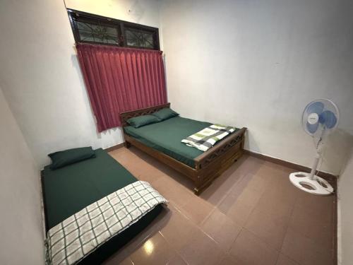 a small room with two beds and a fan at Omah Kawung Homestay Jogja in Demangan
