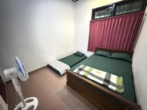 a bedroom with two beds and a fan in it at Omah Kawung Homestay Jogja in Demangan