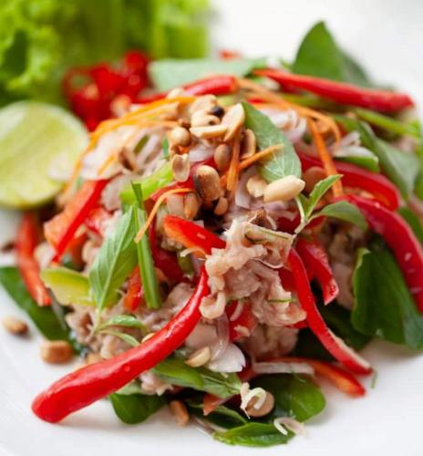 a salad with peppers and vegetables on a white plate at Thisak Resort Cheung phnom kulen in Siem Reap