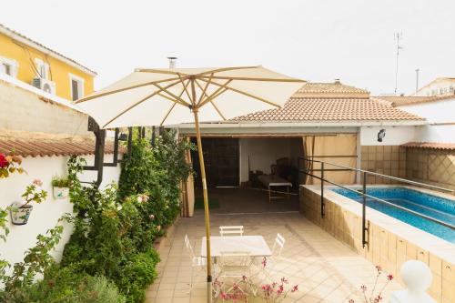 a patio with an umbrella next to a swimming pool at Señorío de Ves in Casas de Ves