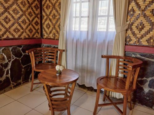 two chairs and a table in a room with a window at Taman Syailendra Cottage Dieng in Dieng