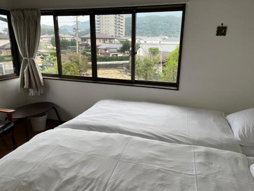 a bedroom with a white bed and a large window at 民宿いとぐるま in Itoshima