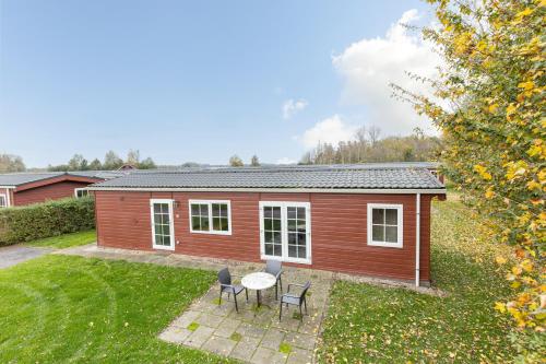 a red house with a table and chairs in a yard at Klein Finland - Chalet 6persoons in Wagenborgen