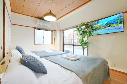 a bedroom with two beds and a flat screen tv at Bohemian Tokyo in Tokyo