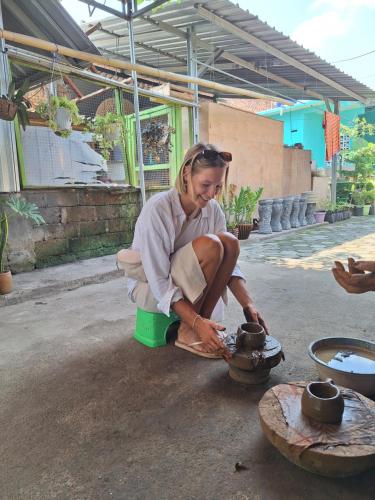 a woman is sitting on a potty with a pot on a table at D' Rinjani View Bungalow in Masbagik