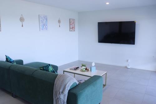 a living room with a couch and a tv at Mountain-Top Ocean View in Coffs Harbour in Coffs Harbour