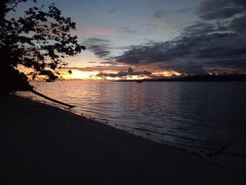 a sunset on the shore of a body of water at Oridek homestay in Kri