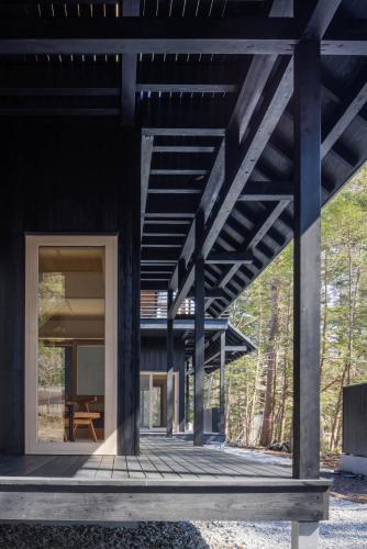 a timber house with a glass door on a deck at SHISHI-IWA HOUSE Karuizawa in Karuizawa