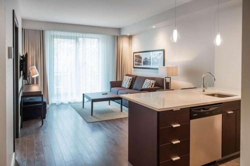 a kitchen and a living room with a couch at Les Suites Victoria, an Ascend Collection Hotel in Gatineau