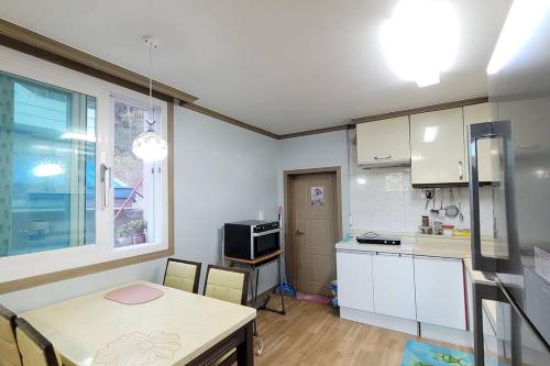 a kitchen with white cabinets and a table and a window at 여유당 라파엘의 집 in Muan