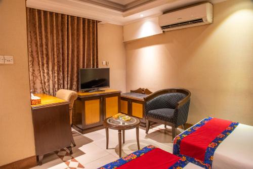 a hotel room with a bed and a desk and a television at Sea Shell Residence - Dhaka in Dhaka