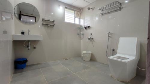 a bathroom with a toilet and a sink and a mirror at Encanto Farmstay Resort in Mysore